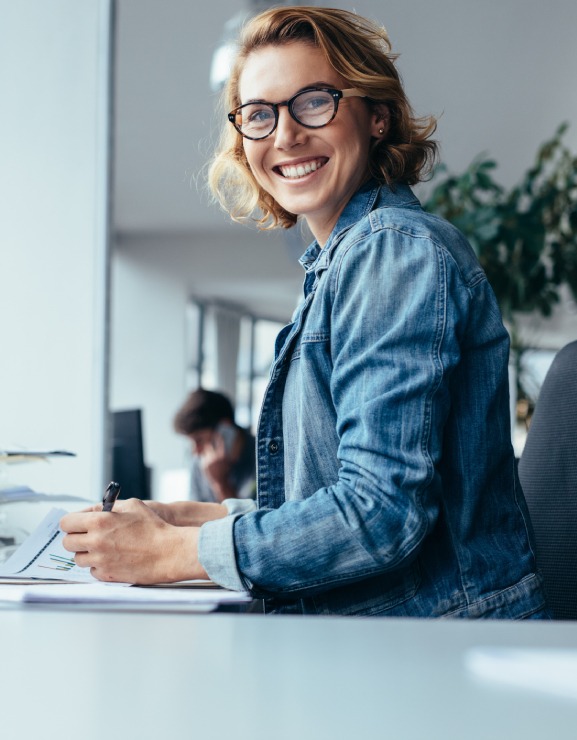 femme blonde souriante assise à un bureau